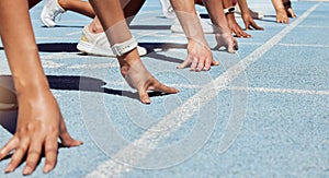 Closeup of determined group of athletes in starting position line to begin sprint or run race on sports track stadium