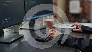 Closeup of developer hands typing code on keyboard while looking at computer screens