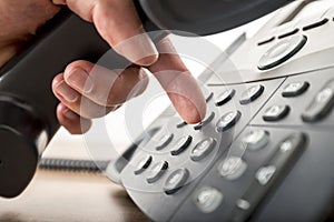 Closeup of dialing a telephone number on a black landline telephone
