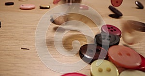 Closeup of different colorful sewing buttons falling on a wooden table. Fashion concept