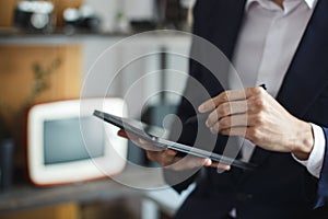 Closeup of digital tablet, successful businessman pointing typing touchpad working at office