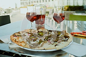 Closeup of a dining table set with a plate of freshly-made pizza and two glasses of wine