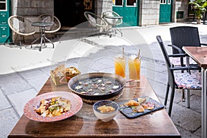 Closeup of a dinner table with Arros Negre, fried chicken, nachos, pita bread and cocktails