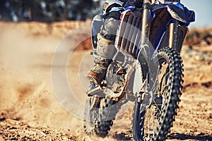 Closeup, dirt track and wheels of motorcyclist with motorbike for race, extreme sports or outdoor competition. Legs of