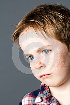 Closeup, disappointed young child with sad blue eyes and freckles