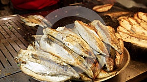 Closeup of dish full of roasted grilled fish. Cooking famous Turkish dish Balik Ekmek on street.