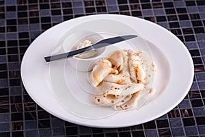 Closeup dish with pancakes and knife and butter on table