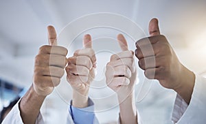 Closeup of diverse group of unknown healthcare professionals using hand gestures to show a thumbs up in the clinic