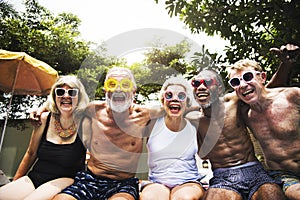 Closeup of diverse senior adults sitting by the pool enjoying su