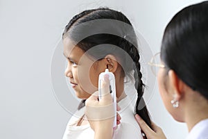 Closeup of Doctor examines or treatment child patient temperature in the ear using electronic thermometer on white background,