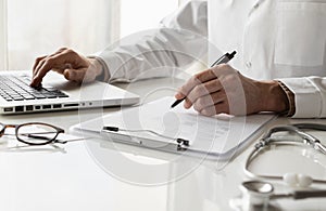 Closeup of doctor medical professional wearing uniform taking notes, physician, therapist or practitioner filling medical document