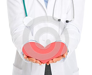Closeup on doctor outstretching paper heart