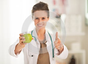 Closeup on doctor showing apple and thumbs up