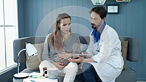 Closeup doctor showing test results in office. Pregnant woman looking tablet