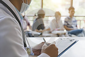 closeup doctor with stethoscope, patients are on background