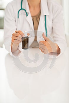 Closeup on doctor woman showing medicine bottle an