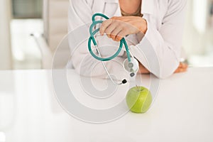 Closeup on doctor woman with stethoscope and apple