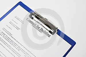 Closeup of a document entitled Contract for building on a blue clipboard