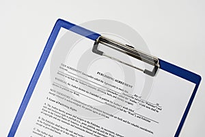 Closeup of a document entitled Publishing agreement on a blue clipboard