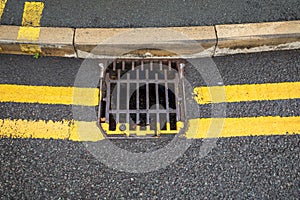 closeup of double yellow line at the kerb side passing over a drainage grid