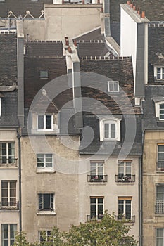 Closeup and downwards view of two very thin buildings, with pink and white walls, windows on the roof, small chimneys