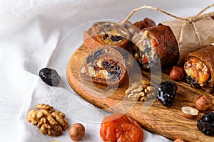 Closeup dried fruit with honey and nuts wrapped in Apple pastille on wooden board white background, fruit roll, healthy dessert,