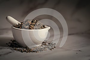 Closeup of Dry Bhringraj leaves, in white ceramic mortar and pestle.