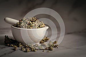 Closeup of Dry Sanjivini Booti leaves, in white ceramic mortar and pestle. photo