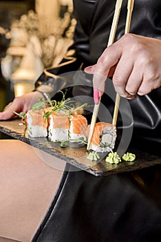 Closeup of eating sushi, young attractive woman eating sushi Philadelphia or California in restaurant.