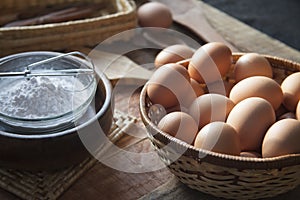 Closeup of eggs in a basket next to a bowl filled with flour on a wooden table