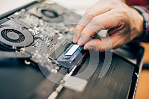 Closeup of electrical engineer technician changing memory in laptop computer photo