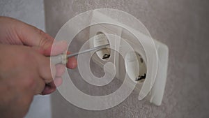 Closeup of electrician hands with screwdriver unscrew outlet