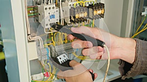 Closeup. Electricians hands testing current electric in control panel. Electrician engineer work tester measuring