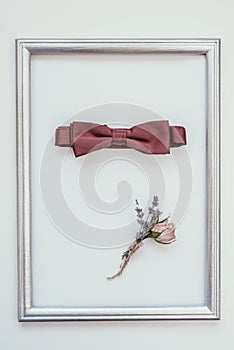 Closeup of elegant stylish brown male accessories isolated on white background in wooden frame. Top view of bow-tie