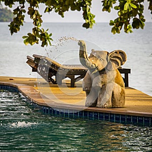 Closeup elephant statue spraying water in a swimming pool next to the sea , Thailand