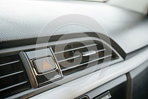 Closeup on emergency button with red triangle icon on car dashboard.