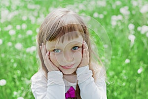 Closeup emotional portrait of cute little girl with beautiful soulful eyes standing on a green meadow