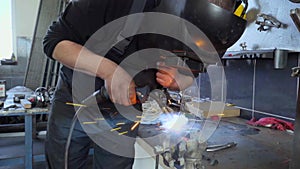 Closeup employee in a mask doing the welding in a workshop