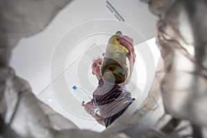 Closeup empty glass bottle in male hand, recycling bin and environmental protection concept