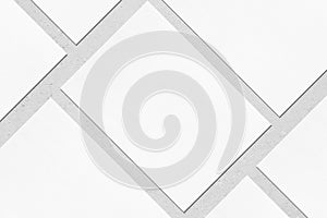 Closeup of empty white rectangle poster mockups lying diagonally on grey concrete background