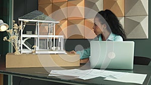 Closeup of engineer using laptop analysis house model structure. Manipulator.
