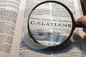 closeup of the epistle of Paul to the Galatians from Bible using a magnifying glass to enlarge print.