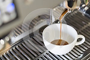 Closeup espresso pouring to white cup from coffee machine, selec