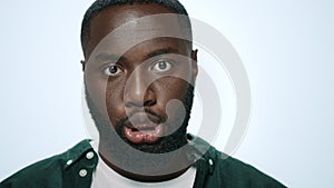 Closeup of excited african american man making funny faces in grey background.