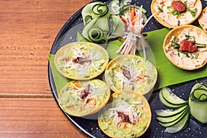 Closeup of exotic Mexican food chalupas of chapulines and chistorra on a black plate