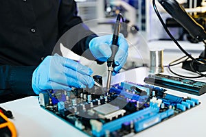 Closeup of expert soldering a green PCB board using precision tools. Ideal for electronics, circuit repair, engineering, tech