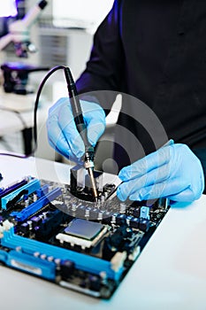 Closeup of expert soldering a green PCB board using precision tools. Ideal for electronics, circuit repair, engineering, tech