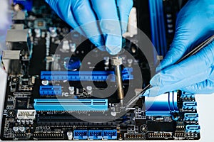 Closeup of expert soldering a green PCB board using precision tools. Ideal for electronics, circuit repair, engineering, tech