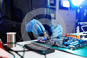 Closeup of expert soldering a green PCB board using precision tools. Ideal for electronics, circuit repair, engineering, tech