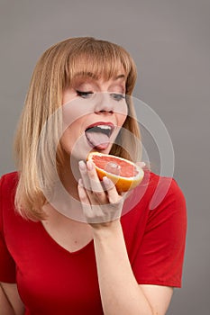 Closeup of extremely joyful adult woman holding grapefruit with great happiness, having big desire to eat delicious